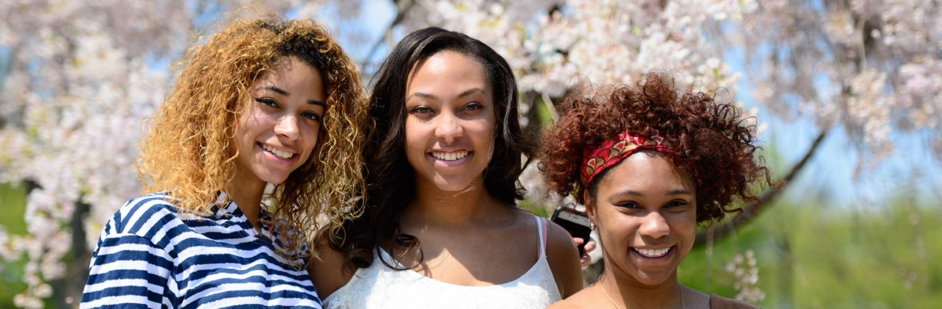 Three students posing for a photo outside in spring
